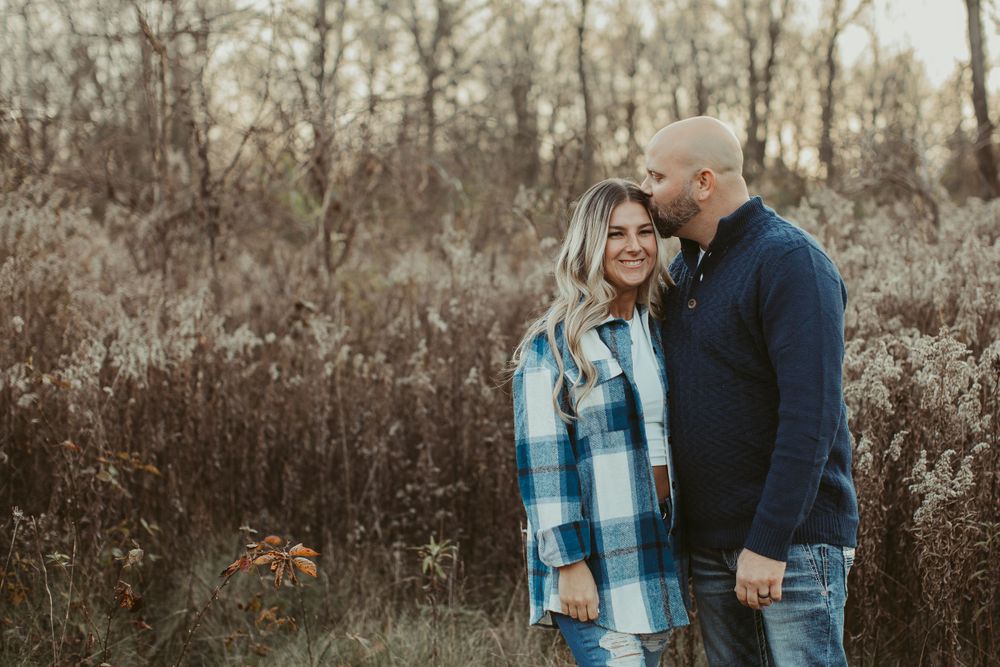 A couple shares a tender moment outdoors wearing coordinated blue and navy outfits.