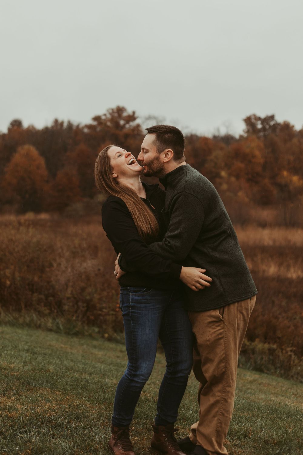 A playful couple embraces during a sunset photoshoot in a fall meadow.