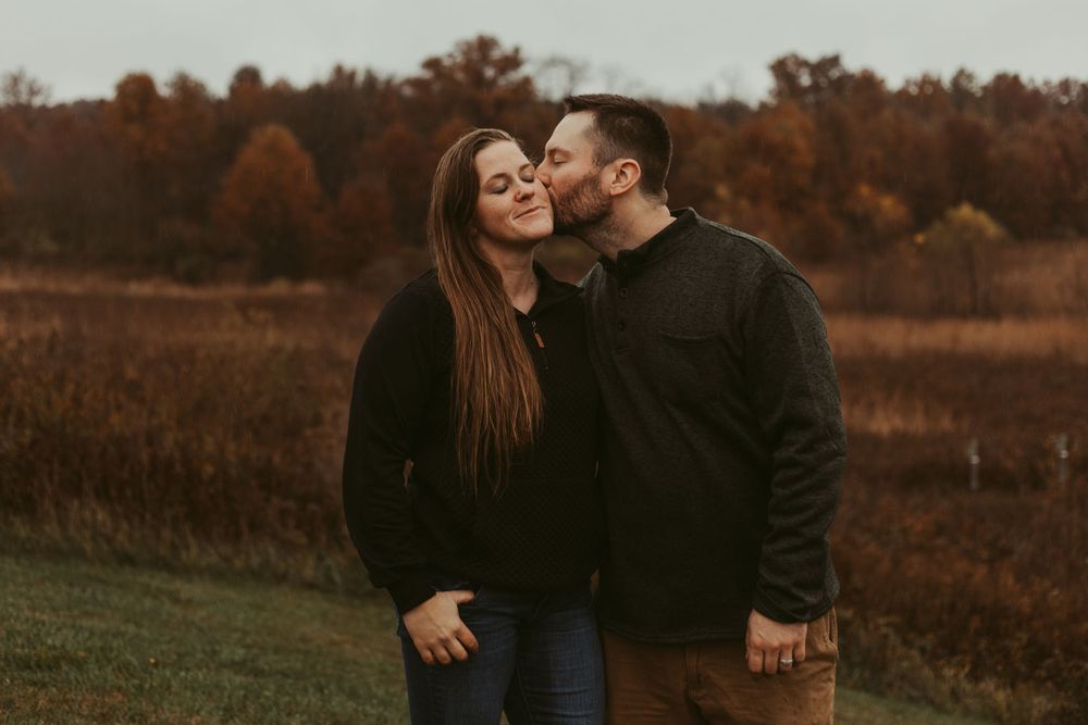 A couple shares an intimate moment during a golden hour photoshoot in an autumn field.