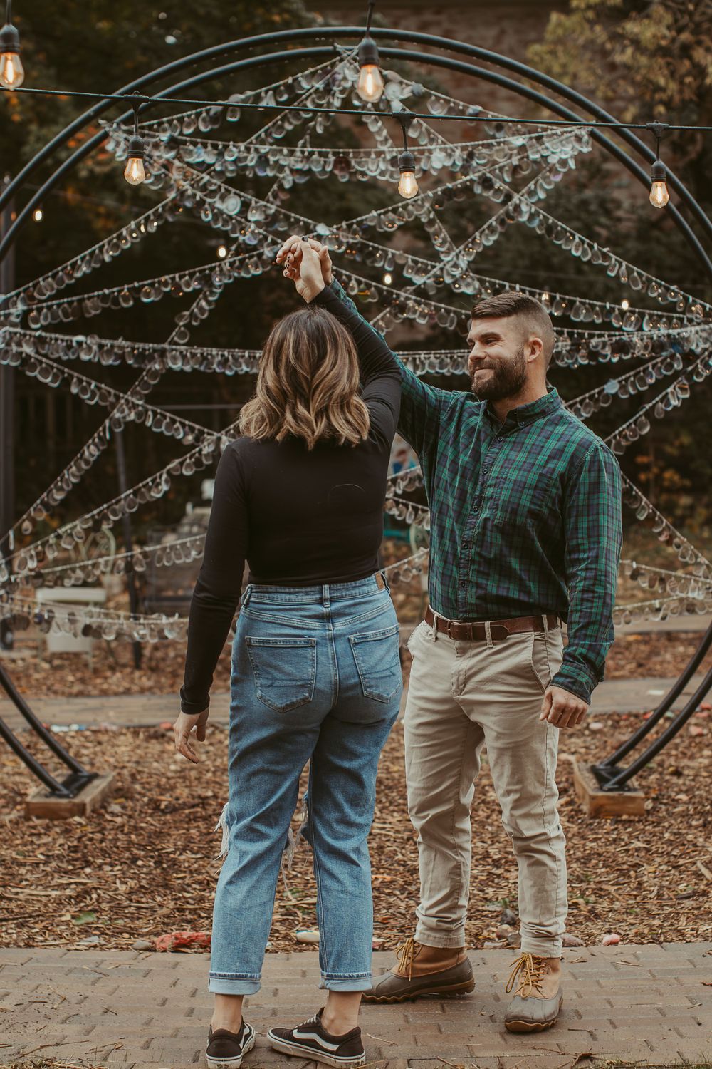 A romantic moment captured under a decorated arch with twinkling lights and crystal strands.
