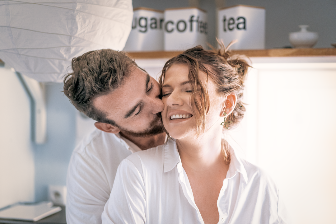 Intimate moment captured in bright modern kitchen with tea storage.