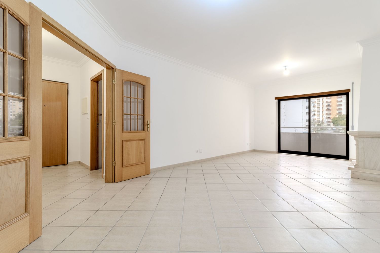 Clean white apartment interior with tiled floors and multiple doorways.