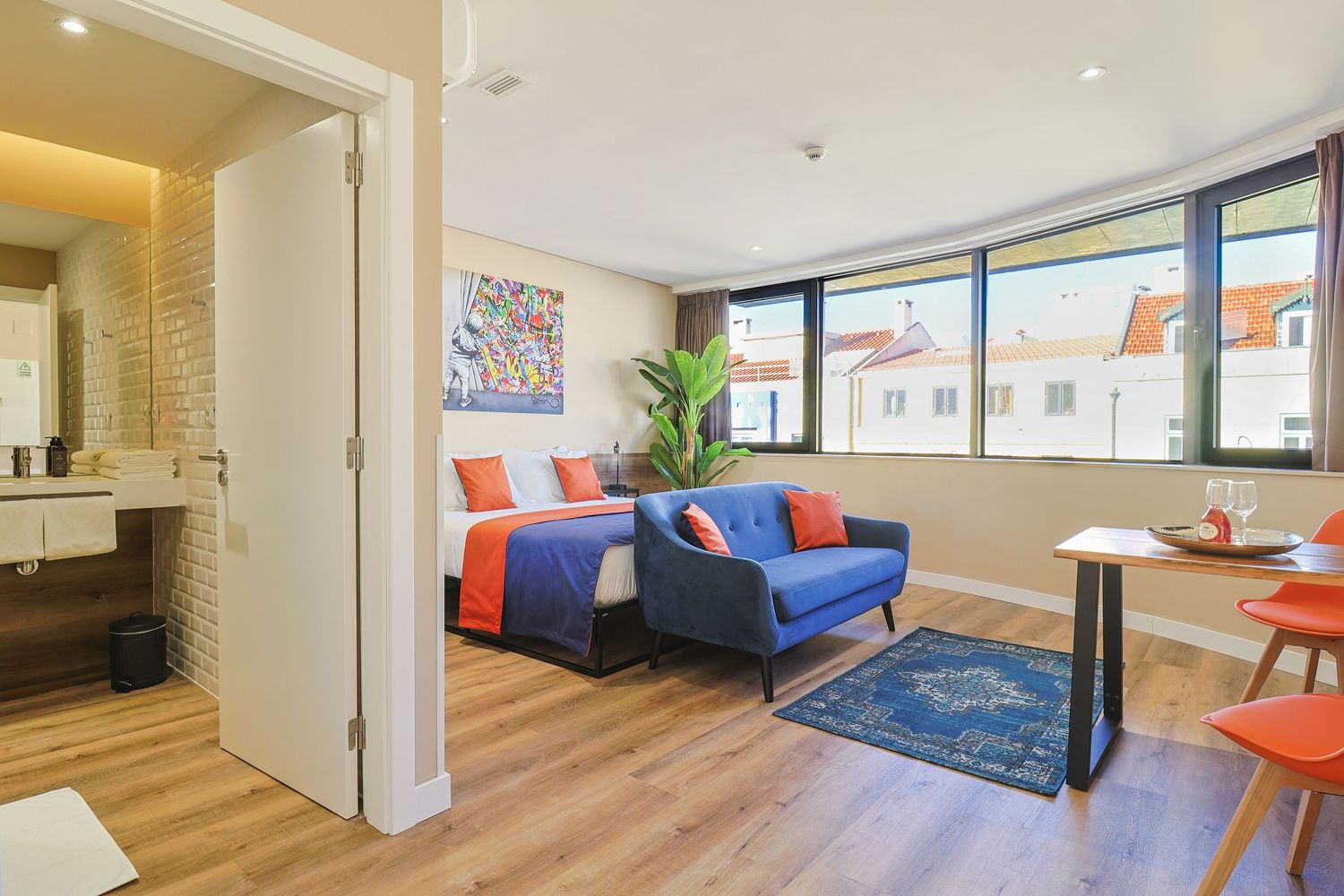 Stylish studio apartment with blue and orange color scheme and modern furnishings.