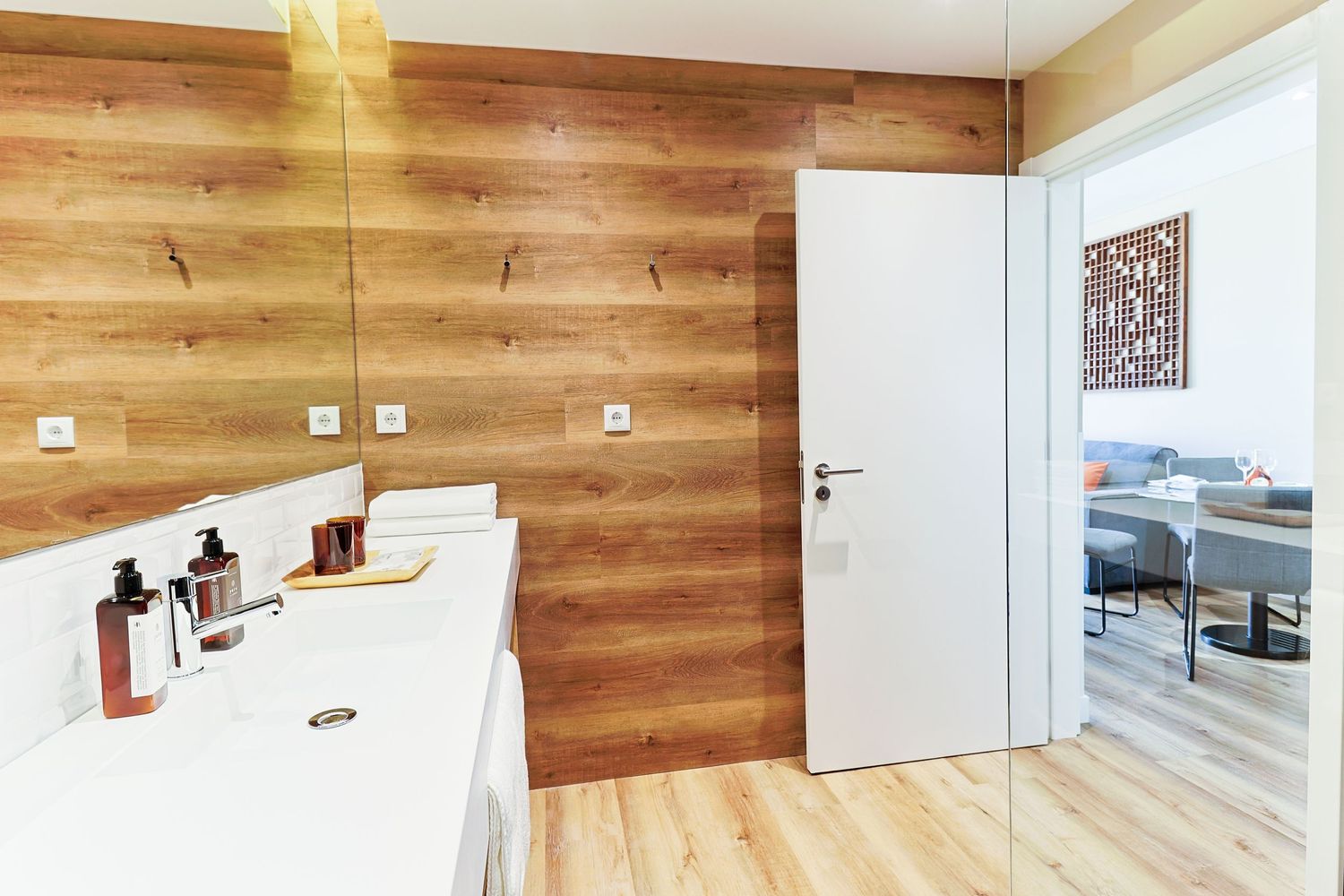 Modern bathroom interior with wooden wall panels and white countertop.