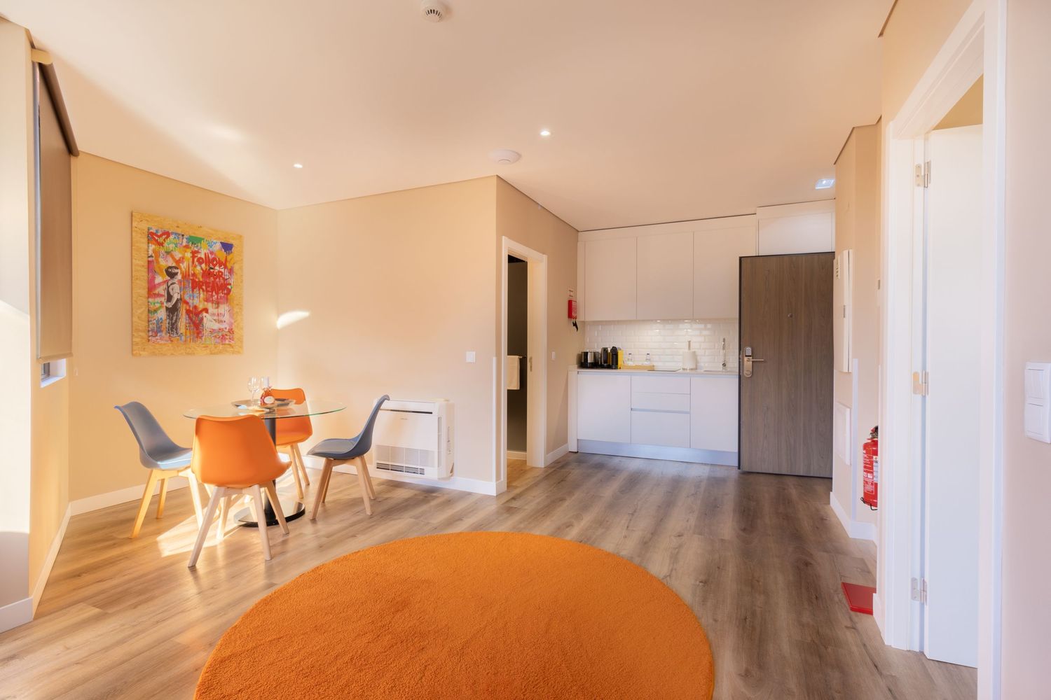 Open concept apartment interior with orange and white dining area and modern finishes.
