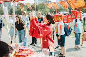 Colorful cultural festival with people gathering outdoors under red decorations and banners.