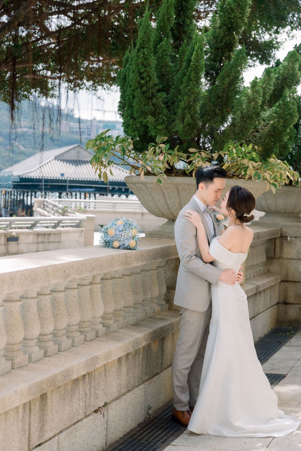 An elegant wedding couple shares intimate moments along a stone terrace with cascading greenery.