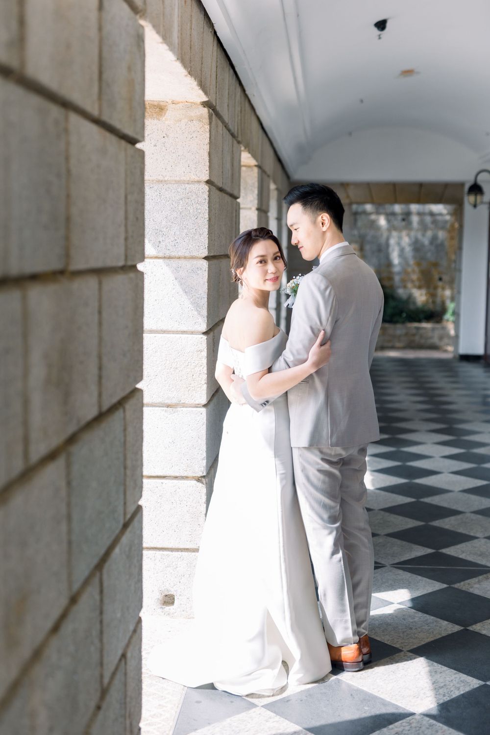 A romantic wedding photo series along a corridor with black and white checkered flooring.