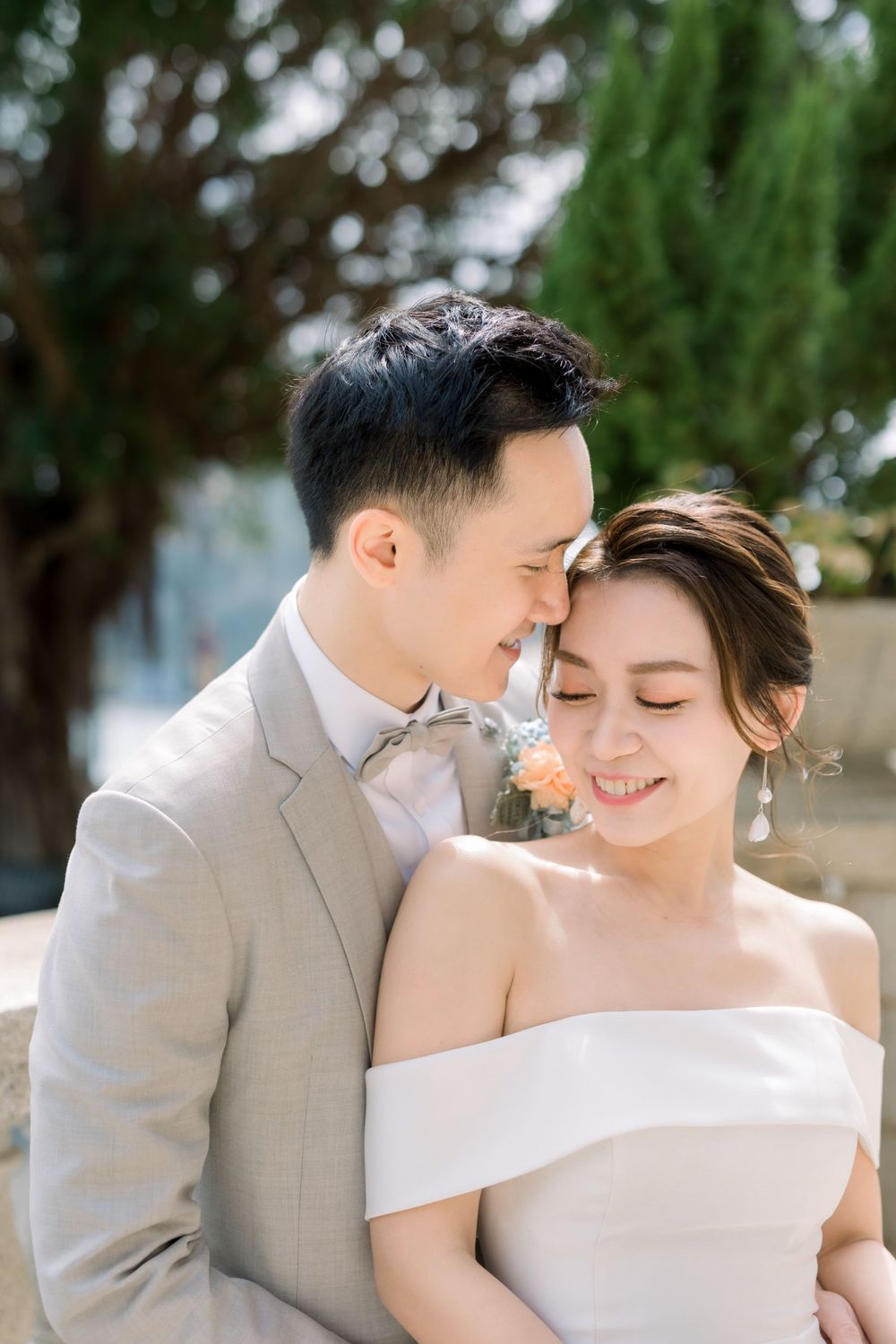 A tender outdoor wedding moment between a couple with the bride in an off-shoulder gown.
