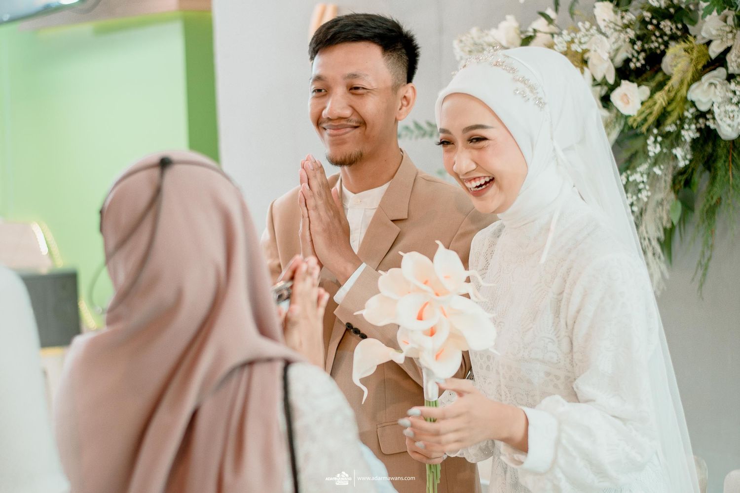 A festive wedding celebration with guests congratulating the couple in traditional attire.