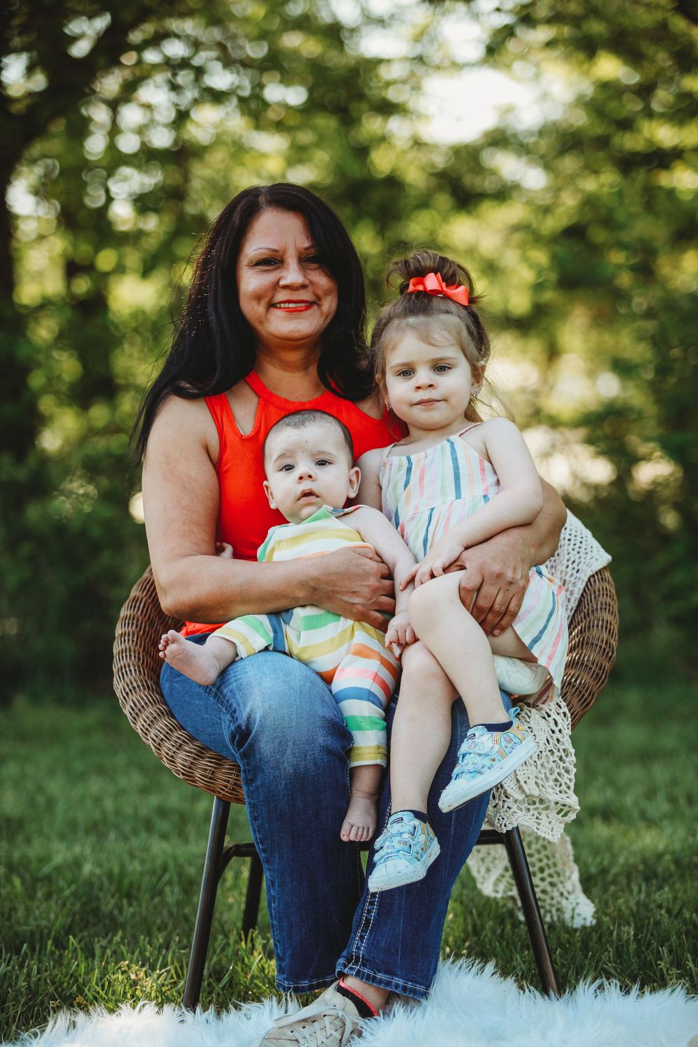 Outdoor portrait of family members sitting in wicker chair on grass.