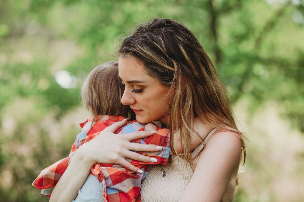 An intimate embrace captured in a sunlit forest setting.