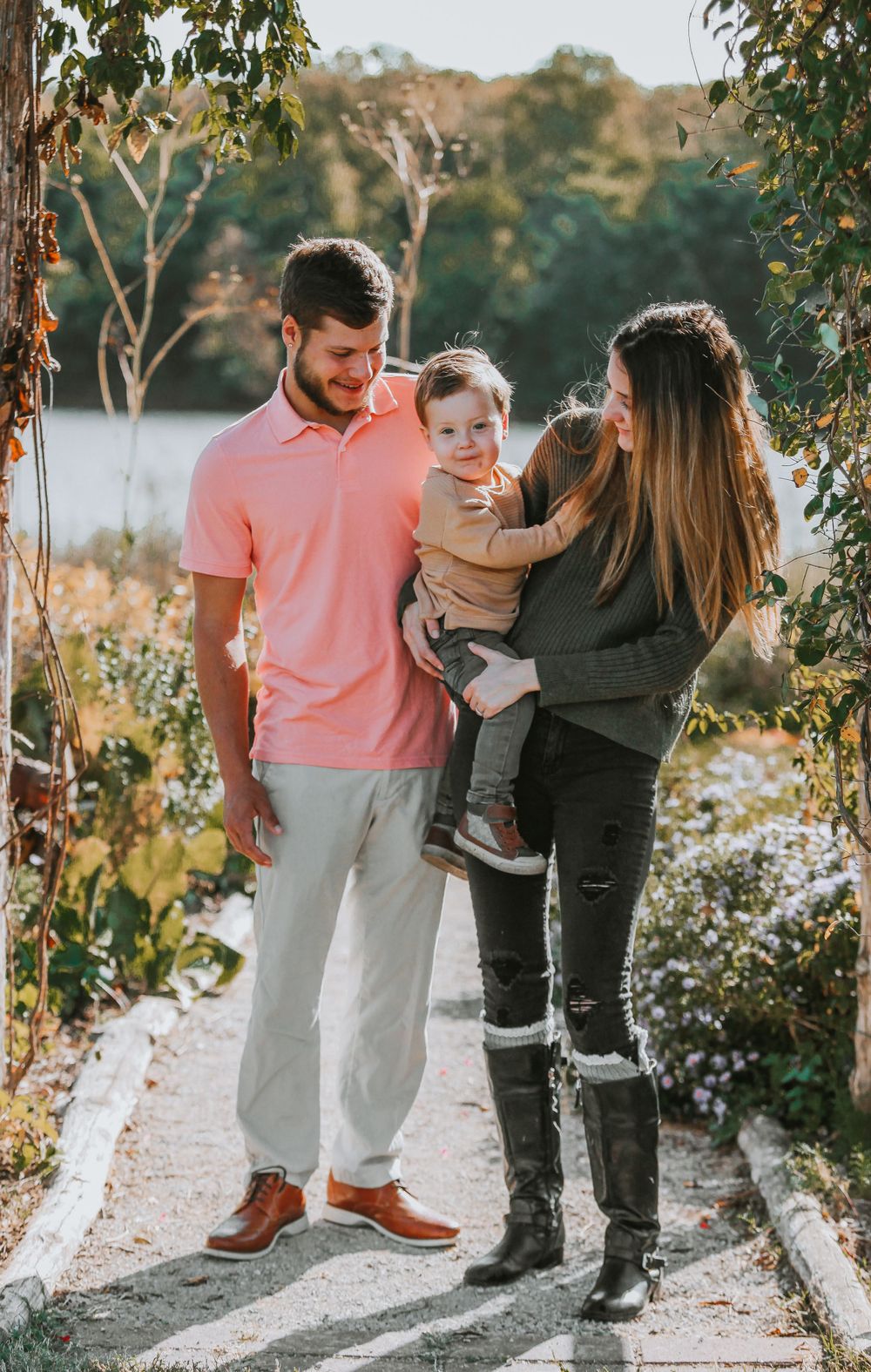 Family enjoying a casual outdoor photoshoot together on a sunny path lined with trees.