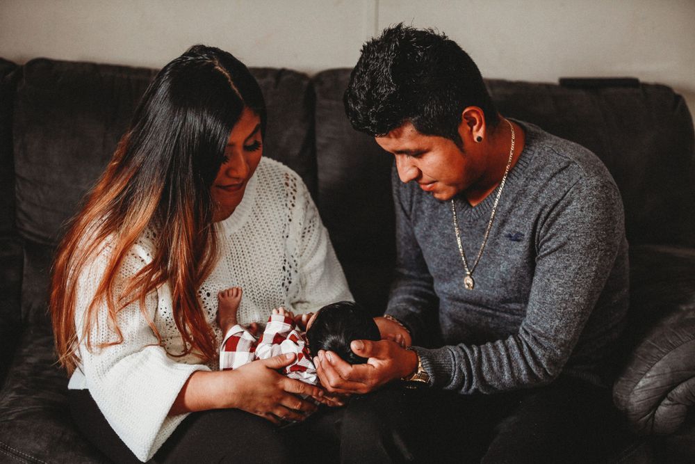 Family sharing intimate moments together on dark couch indoors.