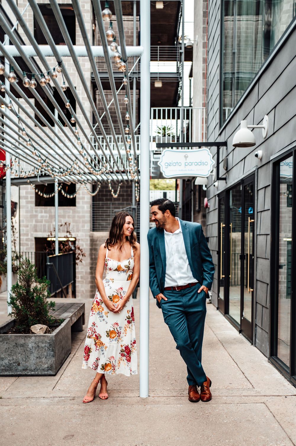 Modern architectural engagement photos with couple sitting in contemporary glass walkway.