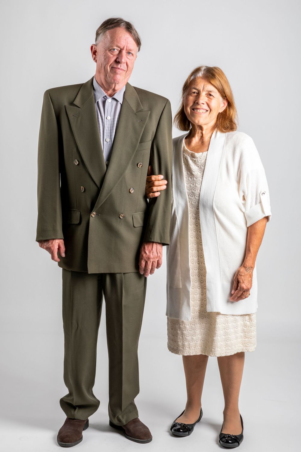 Orange County photographer captures Smiling senior couple in formal attire posing together against neutral gray studio background.
