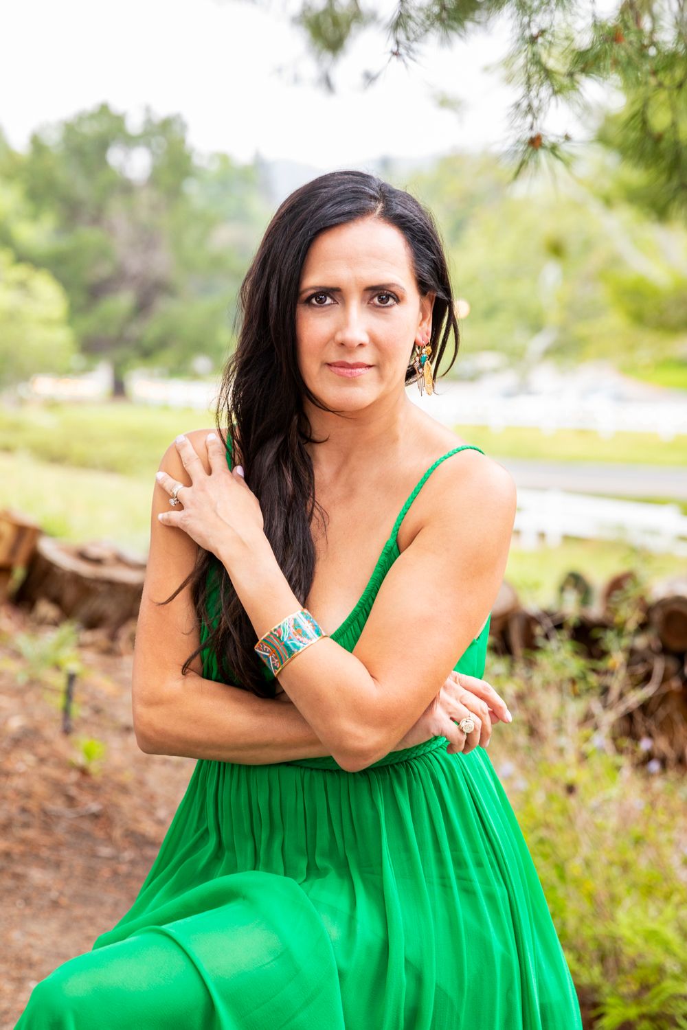 Orange County photographer captures Woman in elegant green dress with turquoise bracelet posing in outdoor garden setting.