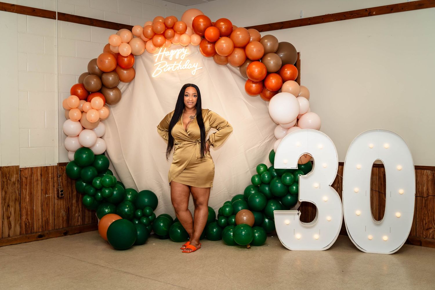 Birthday celebration setup with orange and green balloon arch and large number 30 display.