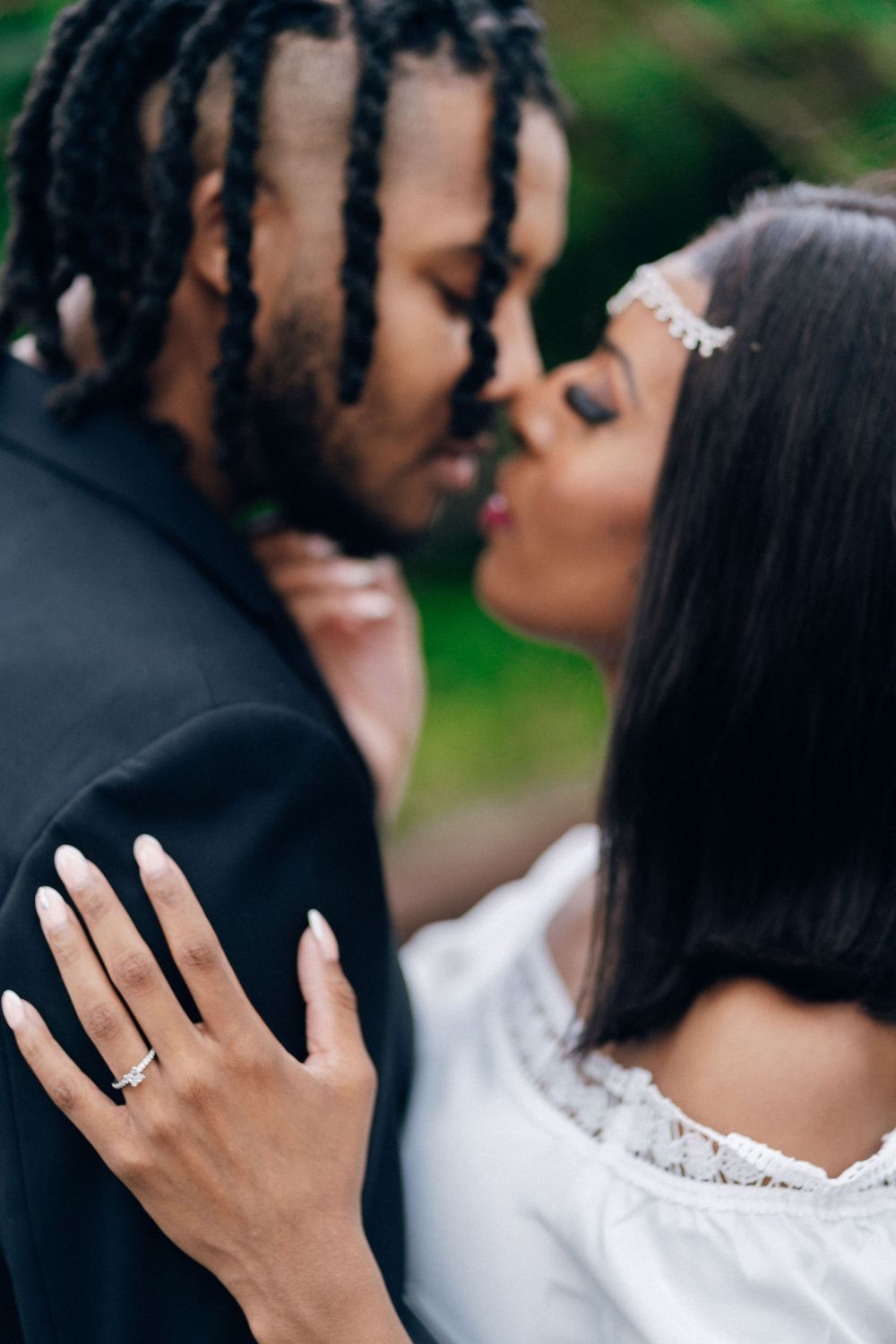 Closeup of a romantic couple sharing a kiss while showing off an engagement ring.