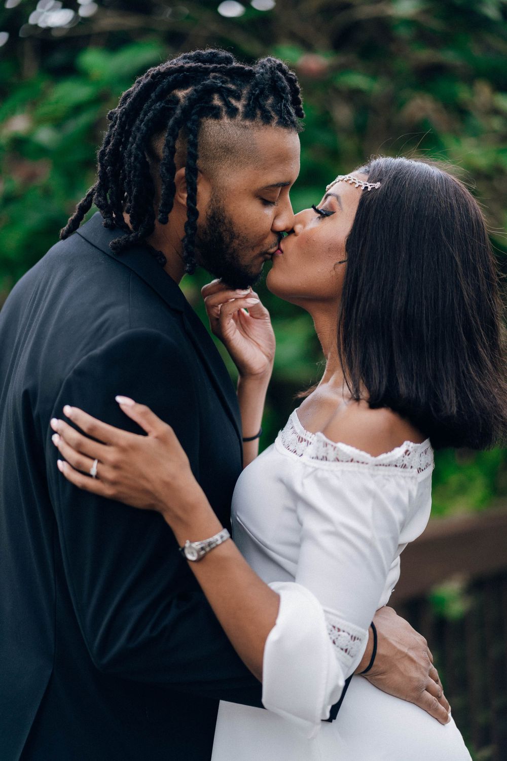 A tender moment between a couple in formal attire sharing an intimate kiss in a garden setting.