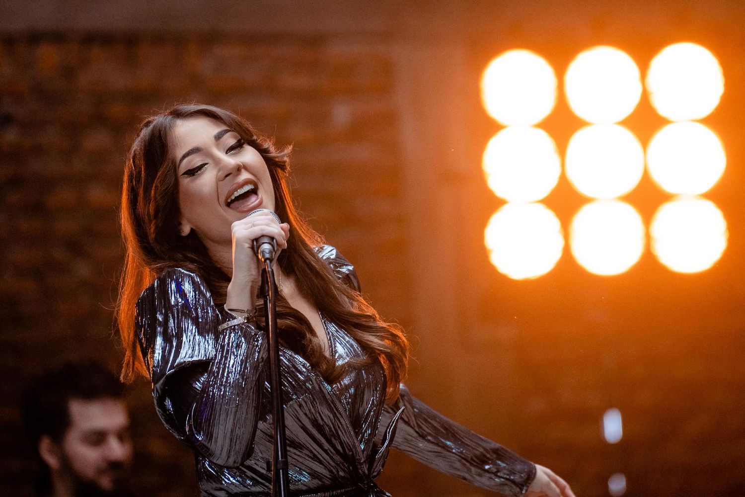 Concert performance with warm orange stage lighting and dramatic backlighting effects.