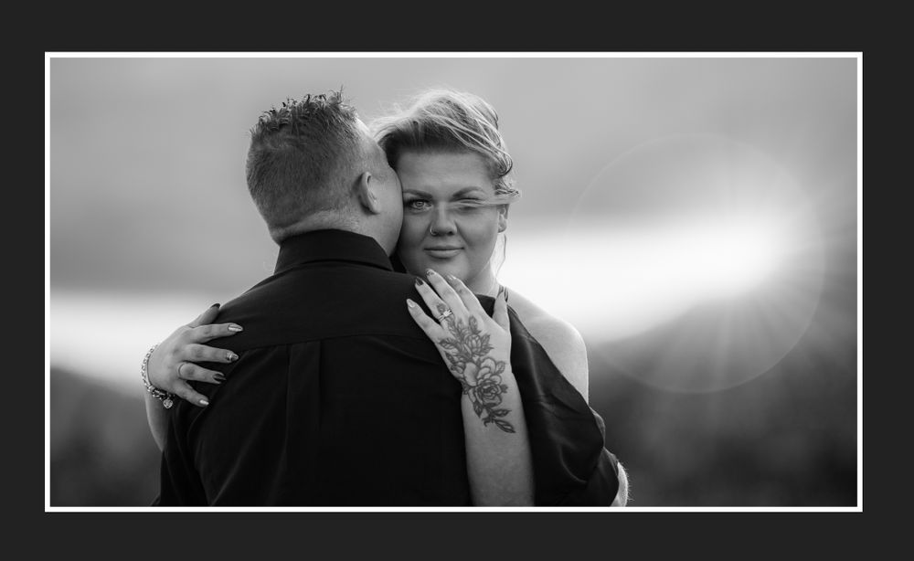 Intimate black and white portrait of couple embracing outdoors.