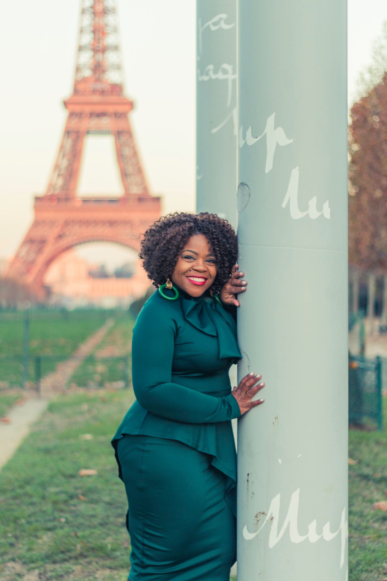 A woman stands alone in front of the Eiffel Tower, taking in the breathtaking view.