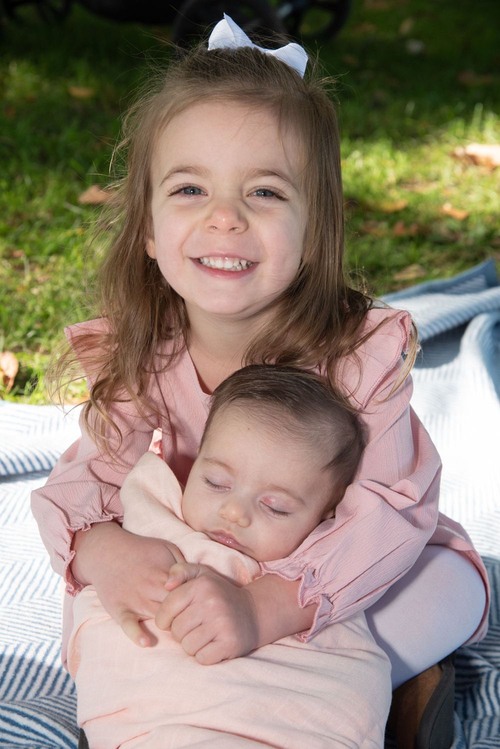 Sweet sibling moment captured on a blanket during outdoor family photoshoot.