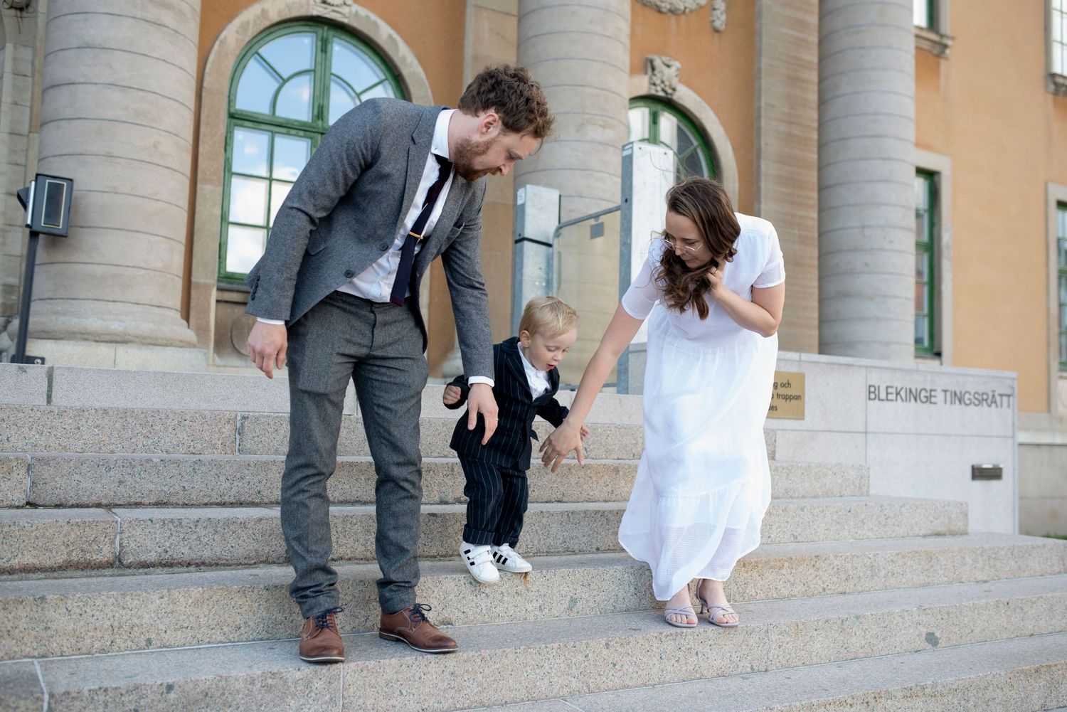 A joyful moment captured on the steps of a building with a couple in formal attire on their wedding day.