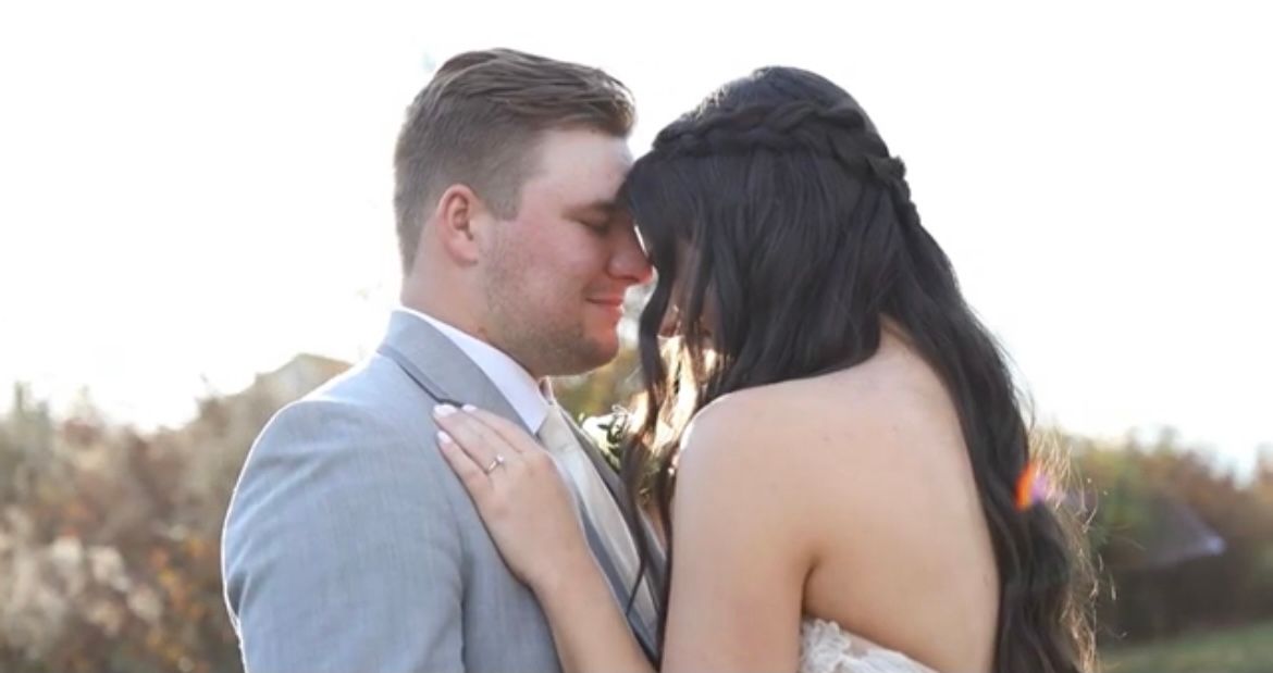 Bride and groom share an intimate forehead-to-forehead moment during their outdoor wedding ceremony at sunset.