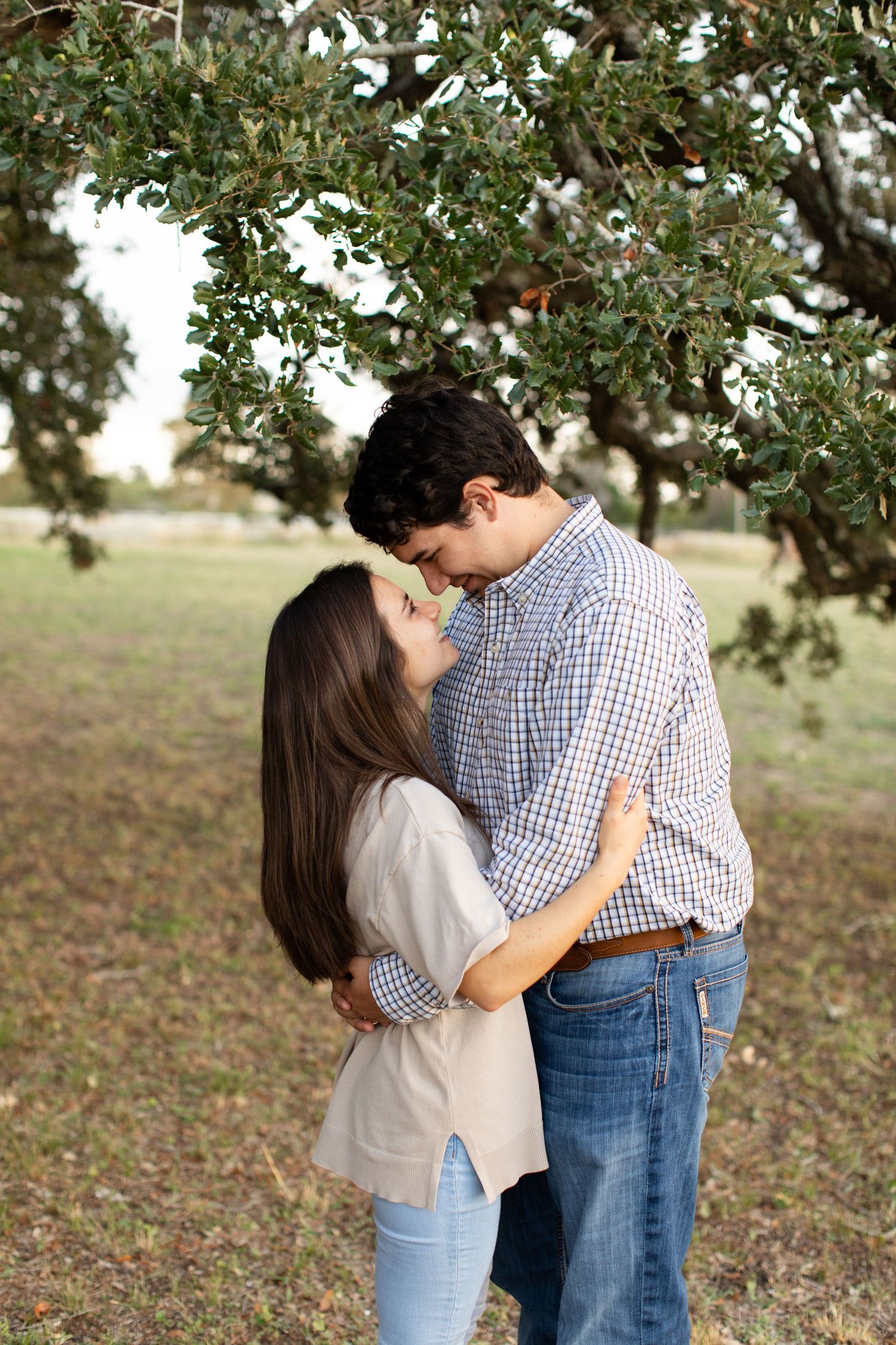 A tender moment shared between two people under a tree canopy.
