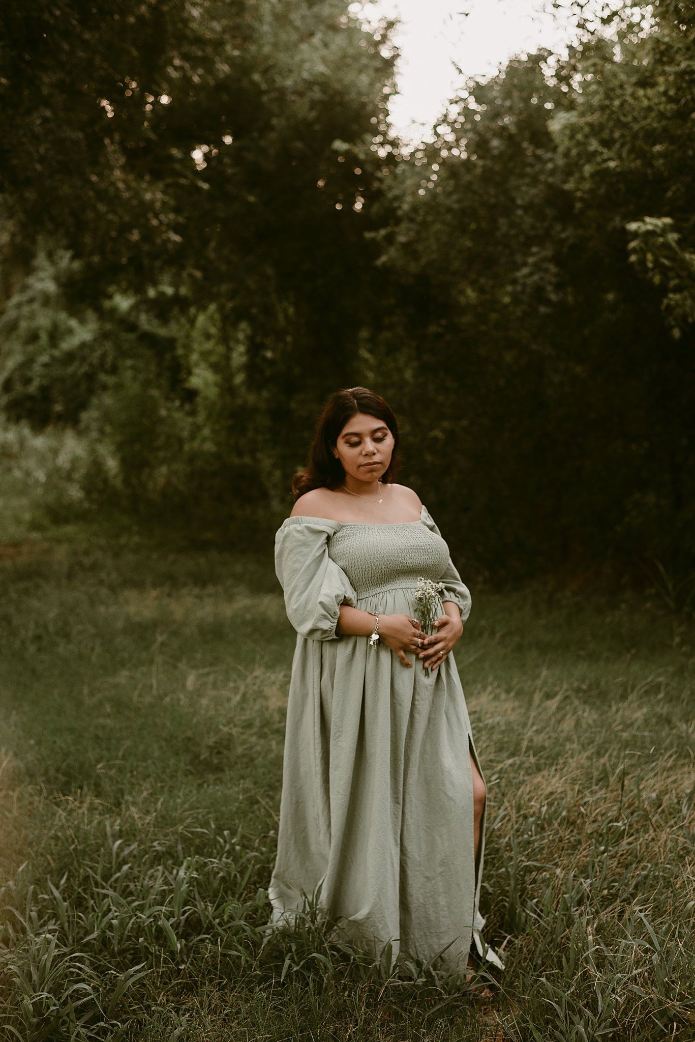 A golden hour portrait in a meadow features someone wearing a billowing light gray dress with bishop sleeves.