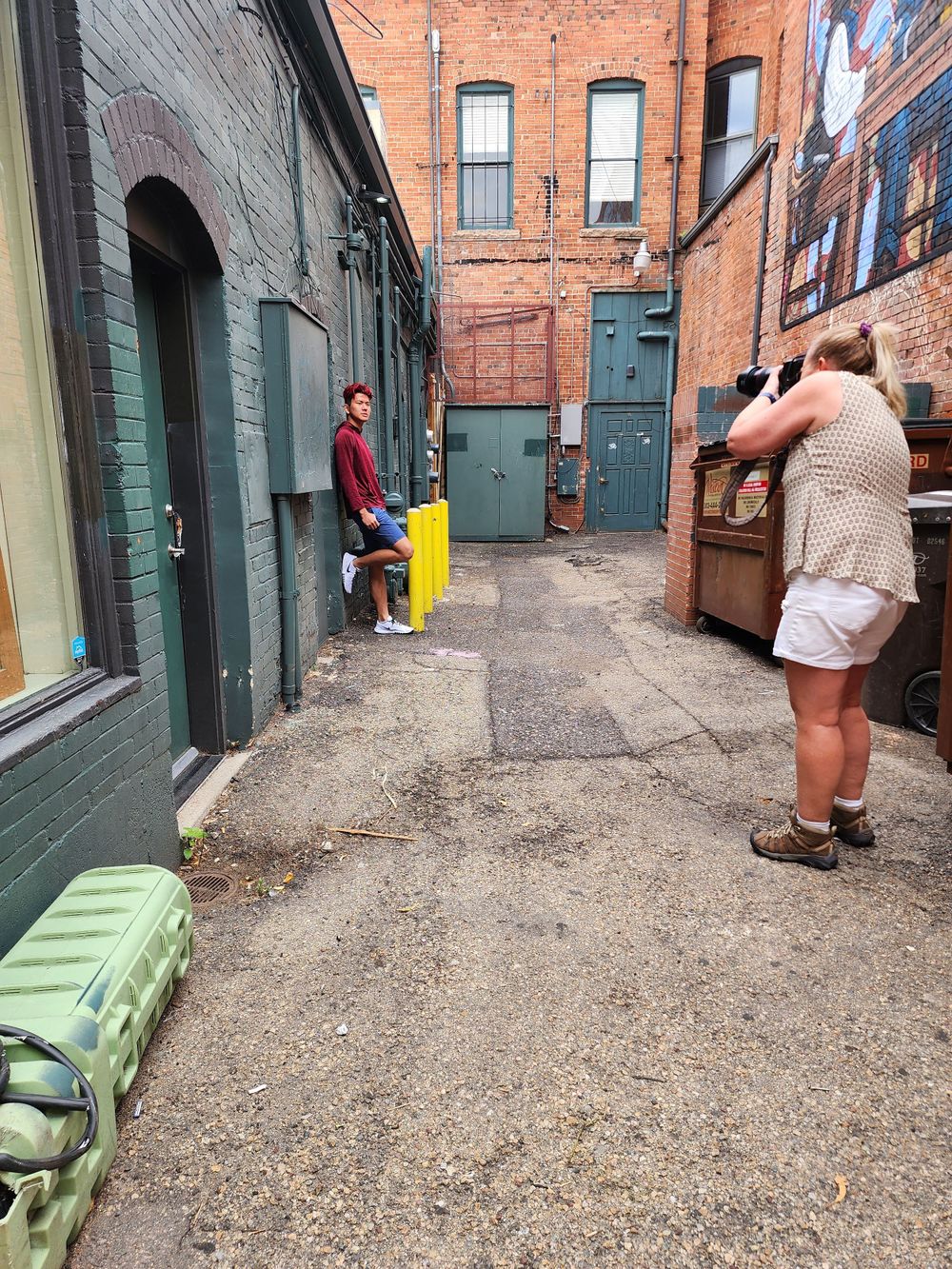 Photographers capture shots in an urban alleyway between red brick buildings.