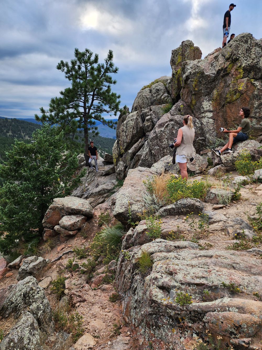 Hikers explore rocky outcrops with sweeping mountain views in the background.