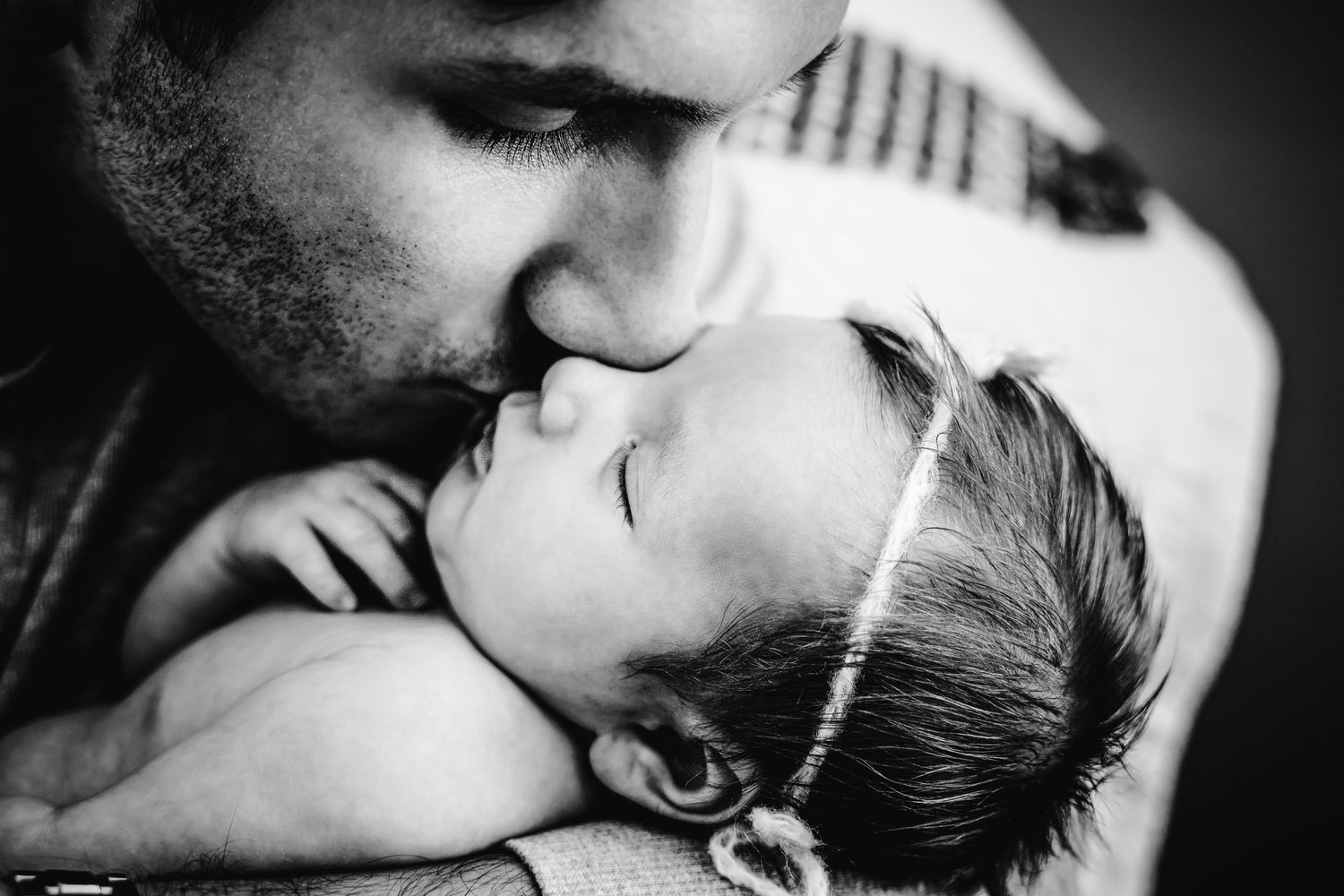 artistic black and white photo of father kissing infant daughter