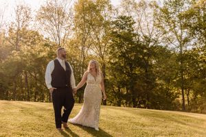 A romantic outdoor photoshoot in a sun-drenched field with autumn trees in the background.