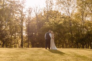 Dreamy sunset wedding photos captured in open field with glowing backlight.