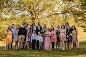 Extended family and wedding guests gather for outdoor photos under fall foliage.