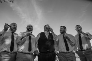 Low angle black and white portrait of groomsmen standing in a row outdoors.