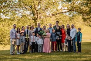 Wedding group portrait with guests arranged in rows on a sunny autumn afternoon.