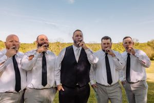 Groomsmen in white shirts and ties pose dramatically in a line outdoors.