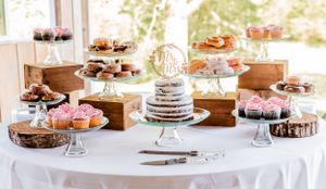 Elegant dessert table with various cakes and treats displayed on glass cake stands.