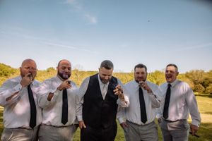 Wedding party members pose together on hillside for creative group shot.