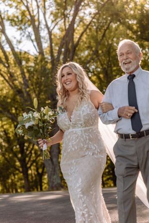 Joyful wedding moment captured during golden hour on a tree-lined path.