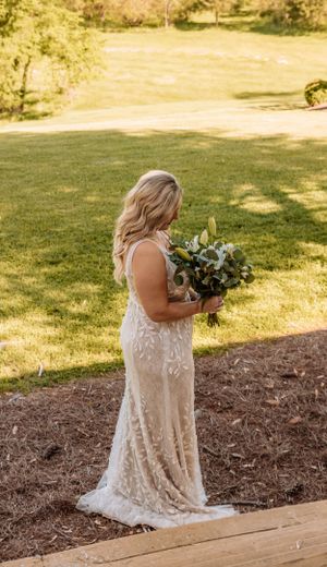 An elegant white lace wedding gown catches sunlight while descending outdoor wooden steps.