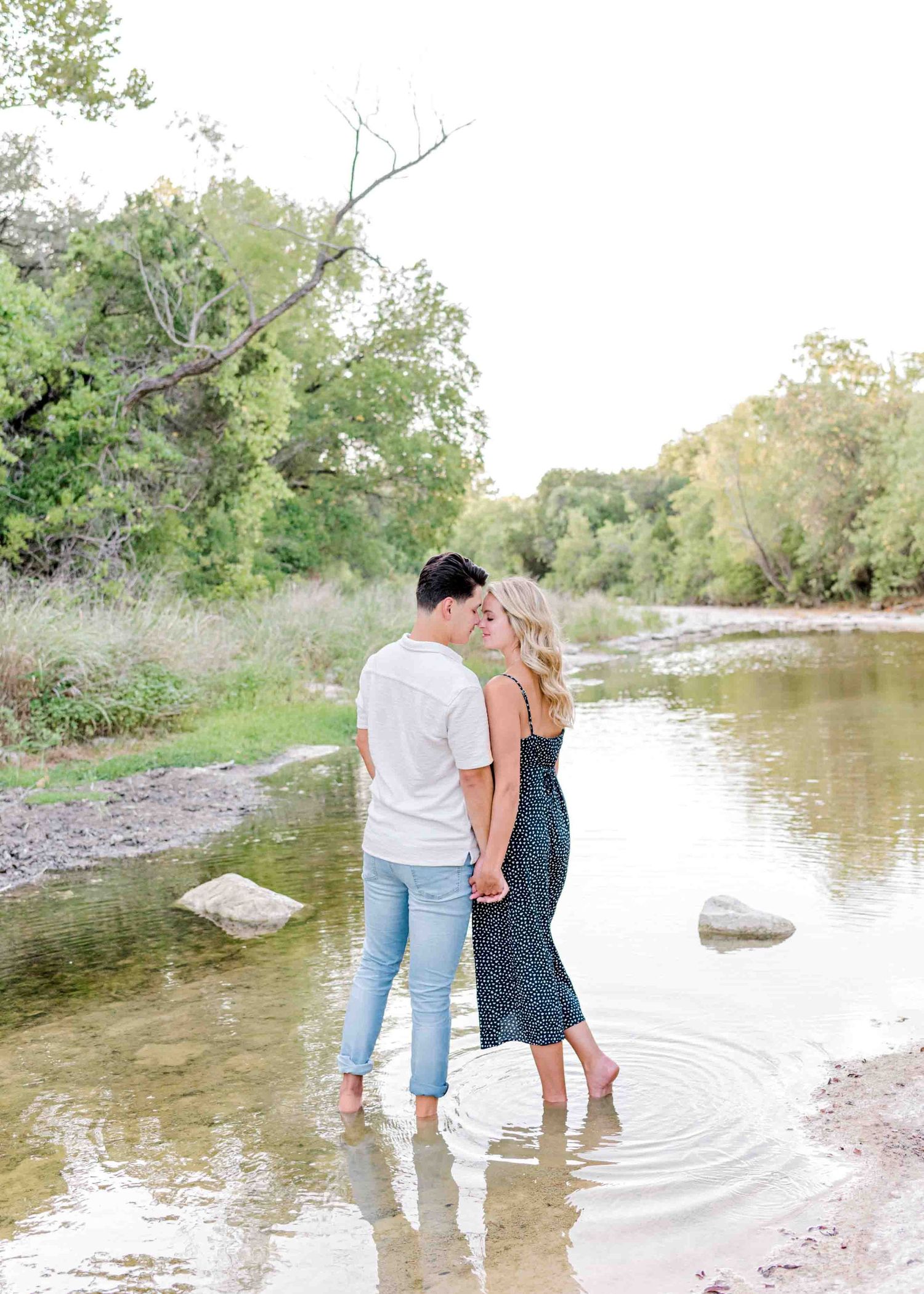 Couple standing together in calm river water with scenic natural background.