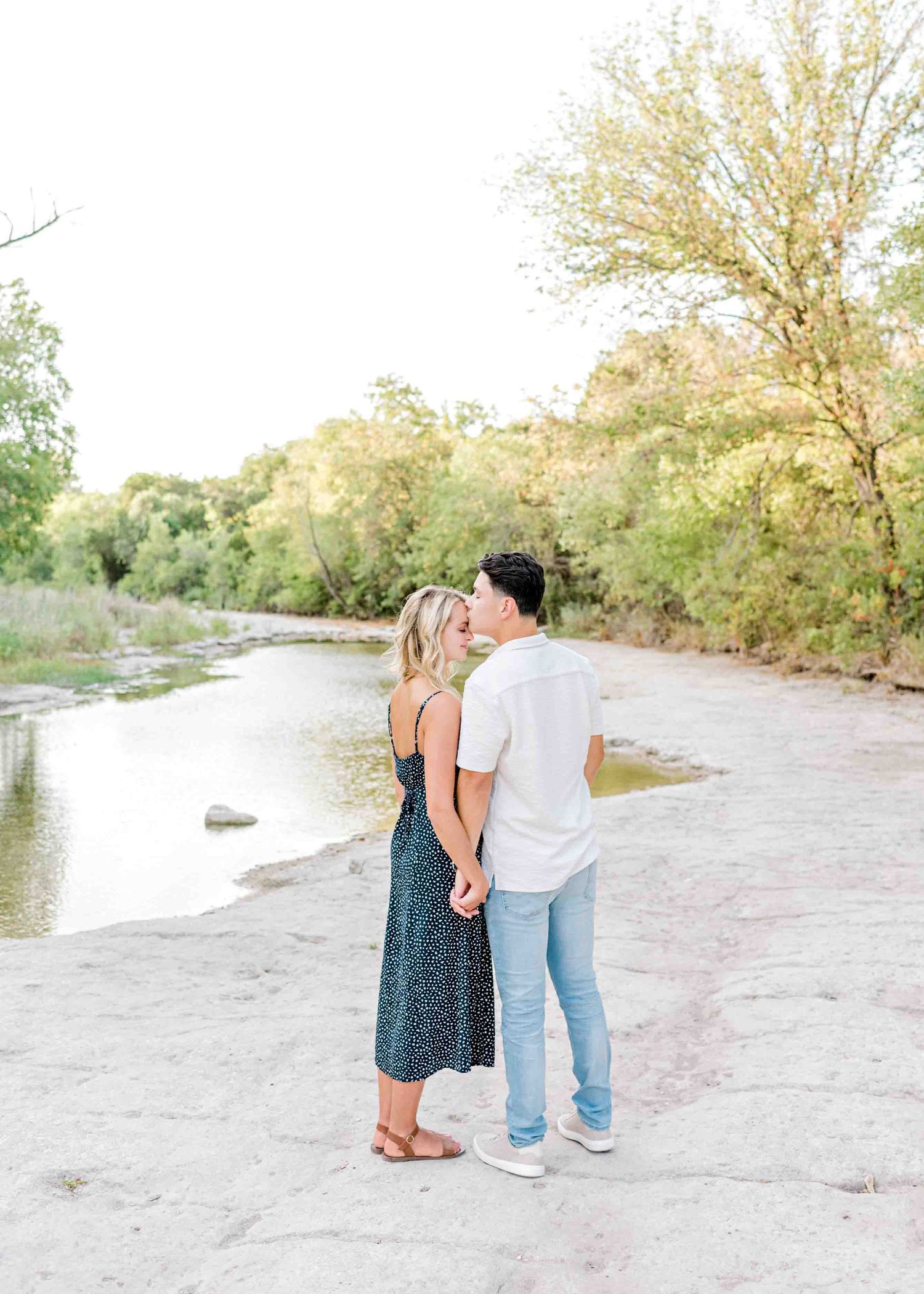 Intimate couple portrait against a scenic backdrop of a river and lush trees.