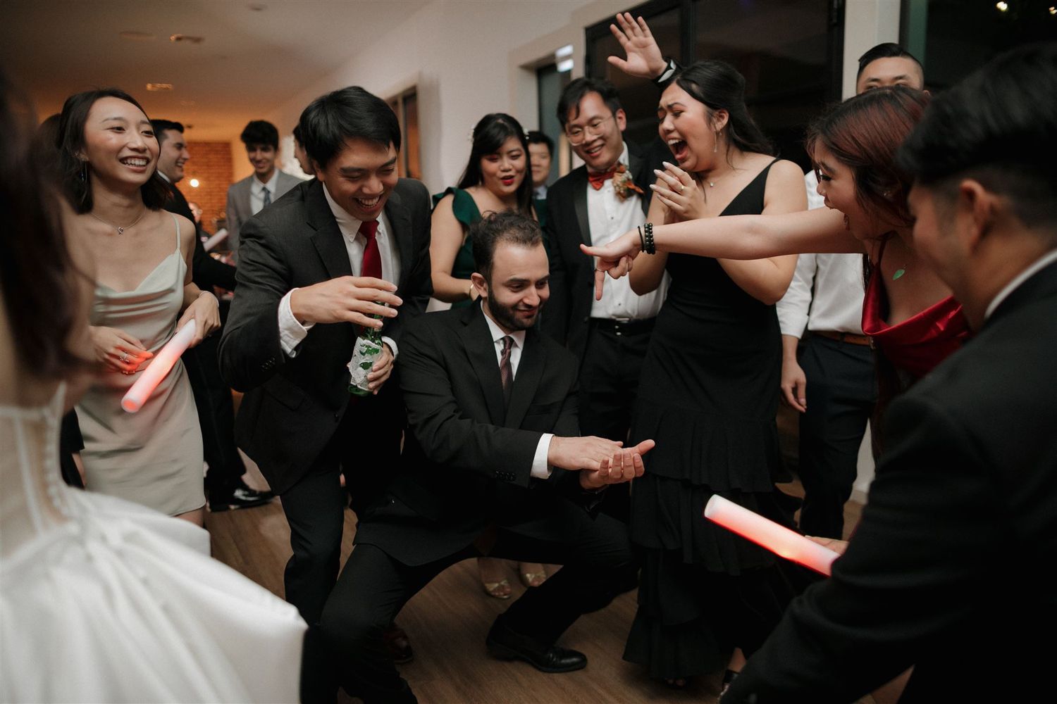 Wedding reception guests dancing and celebrating with excitement on a dance floor.
