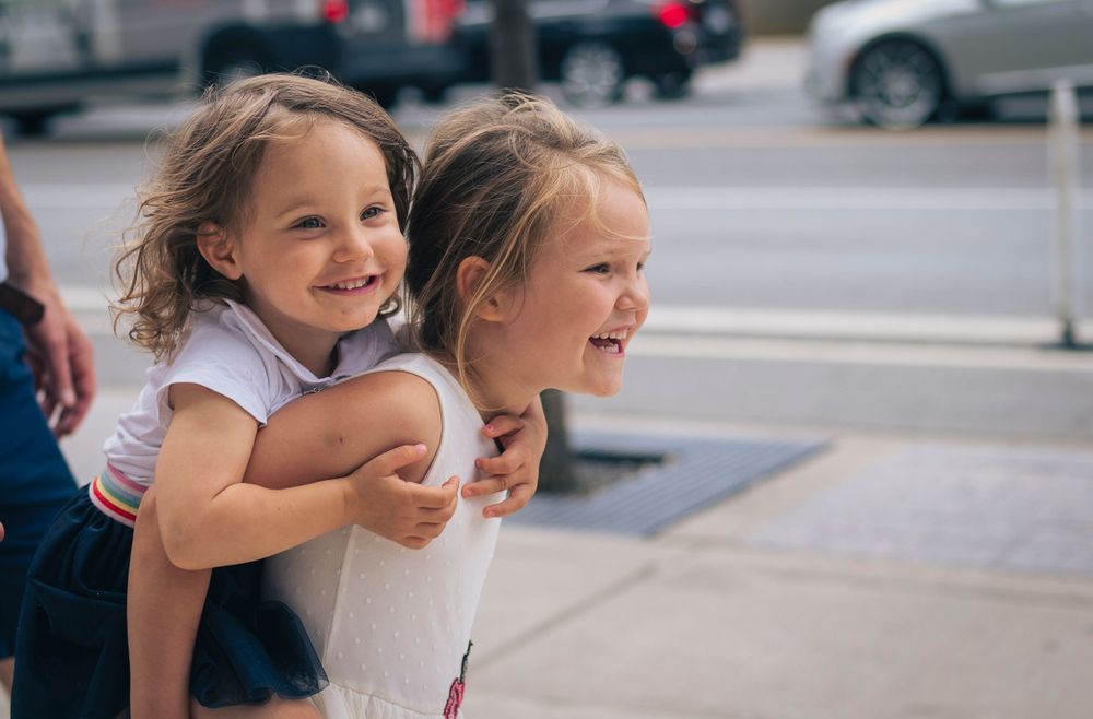 2 children playing. 1 is carrying the other on her back.
