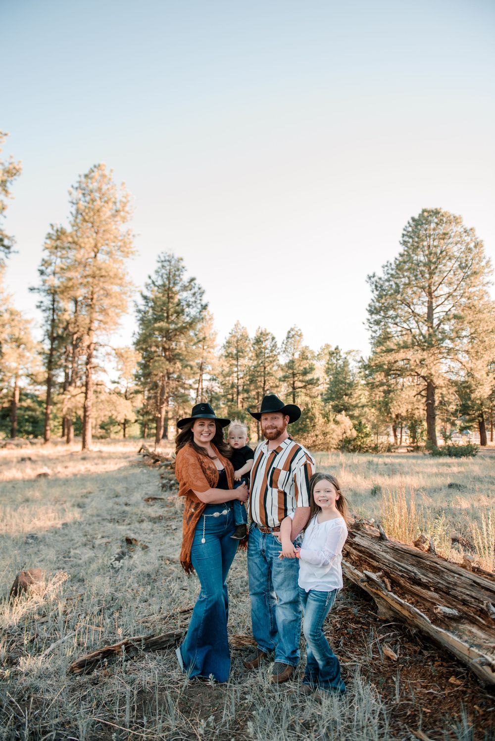 Group photo session in rustic outdoor setting with pine trees at golden hour.